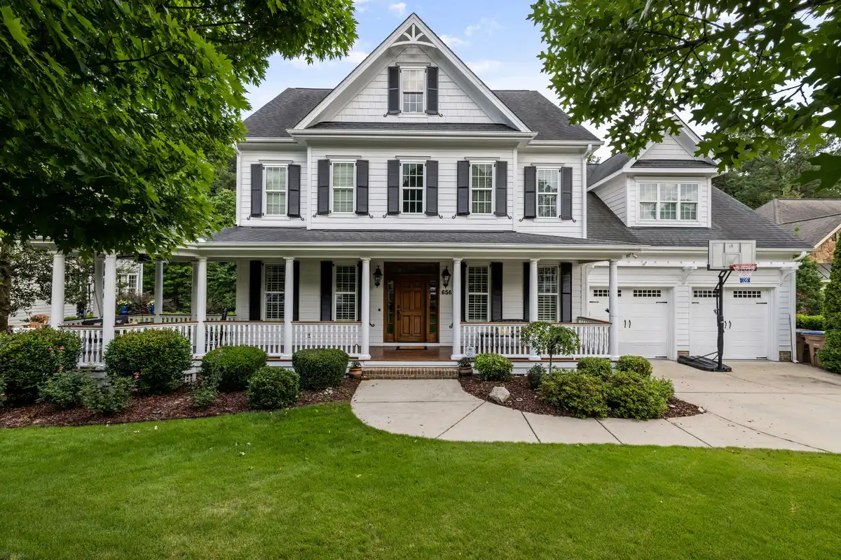 Architectural inspiration: traditional gabled home with a white porch, dark shutters and a landscaped front lawn